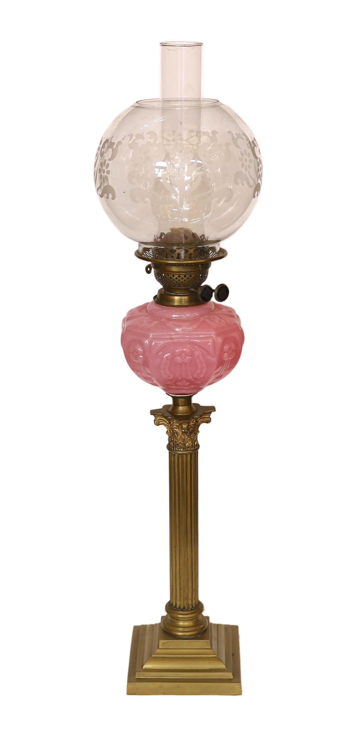 An Edwardian brass Corinthian column oil lamp with opaque pink glass reservoir, etched glass globe and flue, height overall 80cm